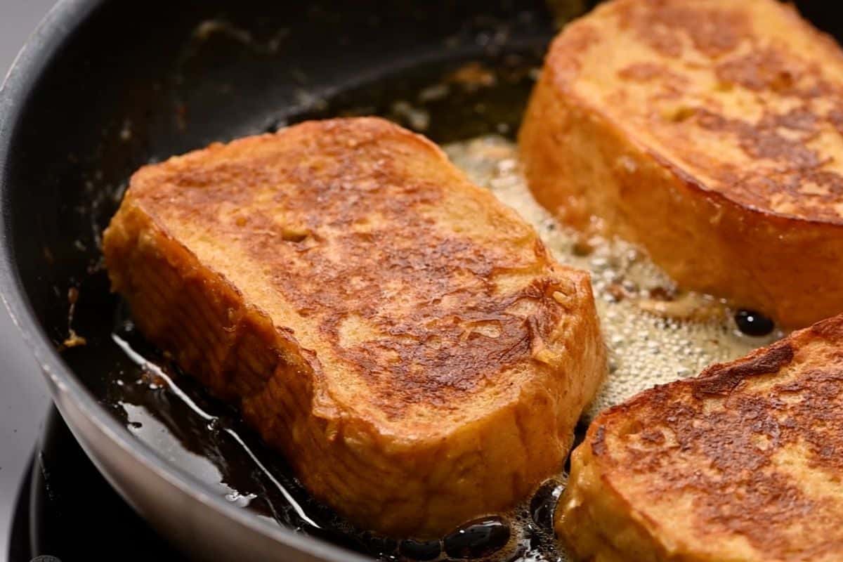 Golden slices of bread in skillet with melted butter.