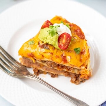 Slice of Instant Pot Taco Lasagna on white plate with Instant Pot in background.