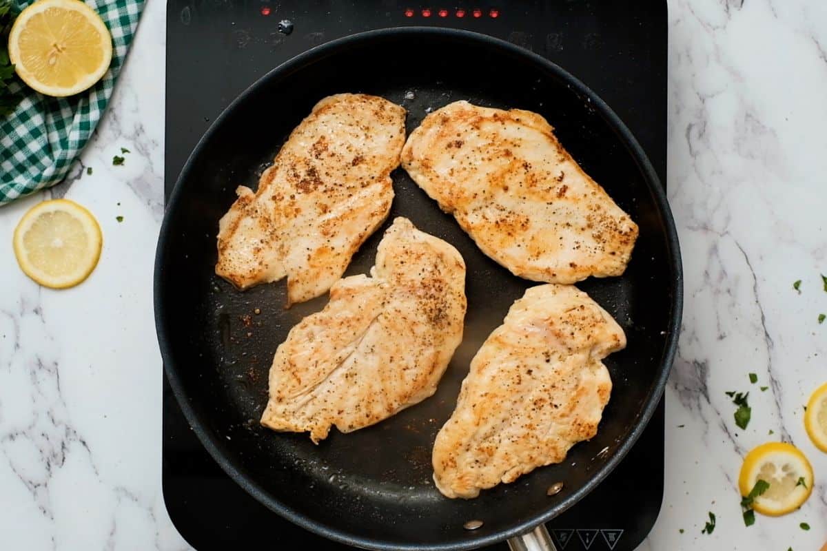 Pan seared chicken cutlets in skillet.
