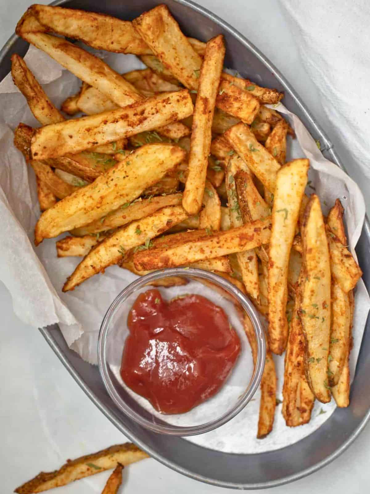 Basket of air fryer homemade fries served with ketchup.