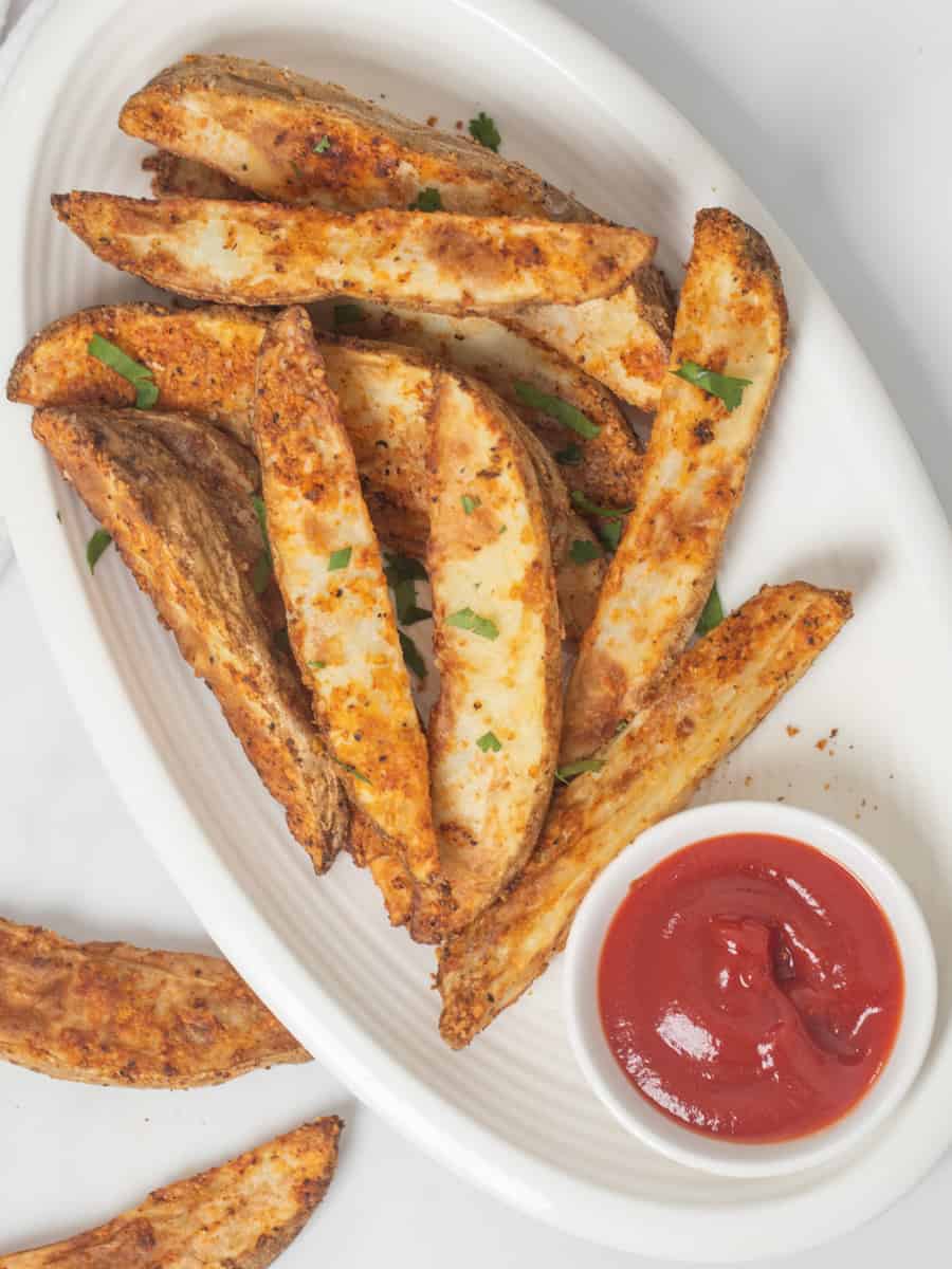 Crispy Air-Fried Potato Wedges on white platter with a side of ketchup.