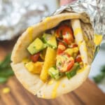 Chicken shawarma in warmed pita with tomato cucumber topping and lemon tahini sauce.