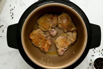Seared boneless skinless chicken thighs inside pressure cooker.