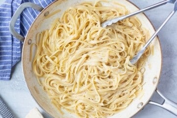 Alfredo noodles in skillet after being cooked in light sauce until pasta is tender.
