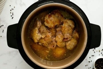 Layered seared chicken thighs in inner pot with teriyaki sauce.