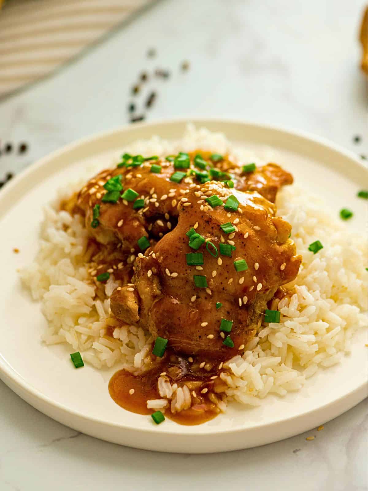 Instant Pot Teriyaki Chicken Thighs served on top of white rice topped with sliced green onions.