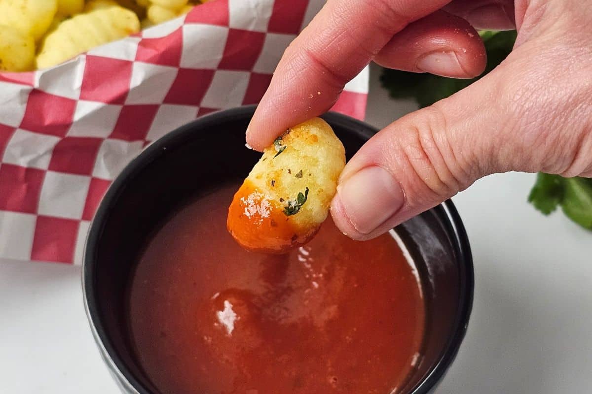 Crispy air-fried gnocchi being dipped into marinara sauce.