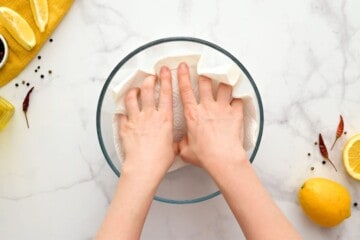 hands using paper towel to dry off shrimp before seasoning.