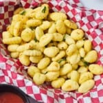 Basket lined with checkered paper filled with Italian seasoned, crispy air-fried gnocchi served with marinara on the side.