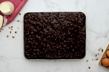 Pecan cocoa frosting poured over chocolate sheet cake.
