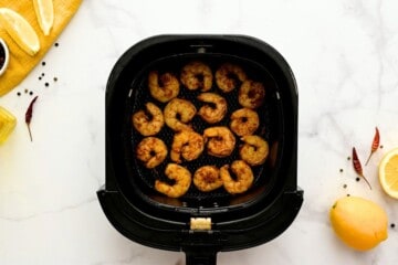 Air-fried shrimp in single layer in air fryer basket.