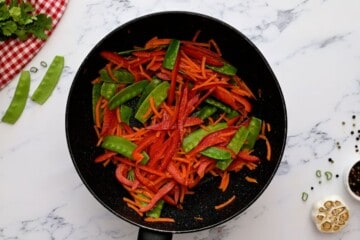 Carrots, peppers, and snap peas in saute pan.