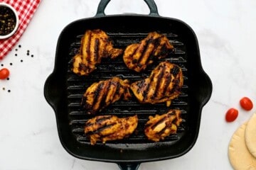 Chicken thighs on grill plate after being marinated in chicken shawarma marinade.