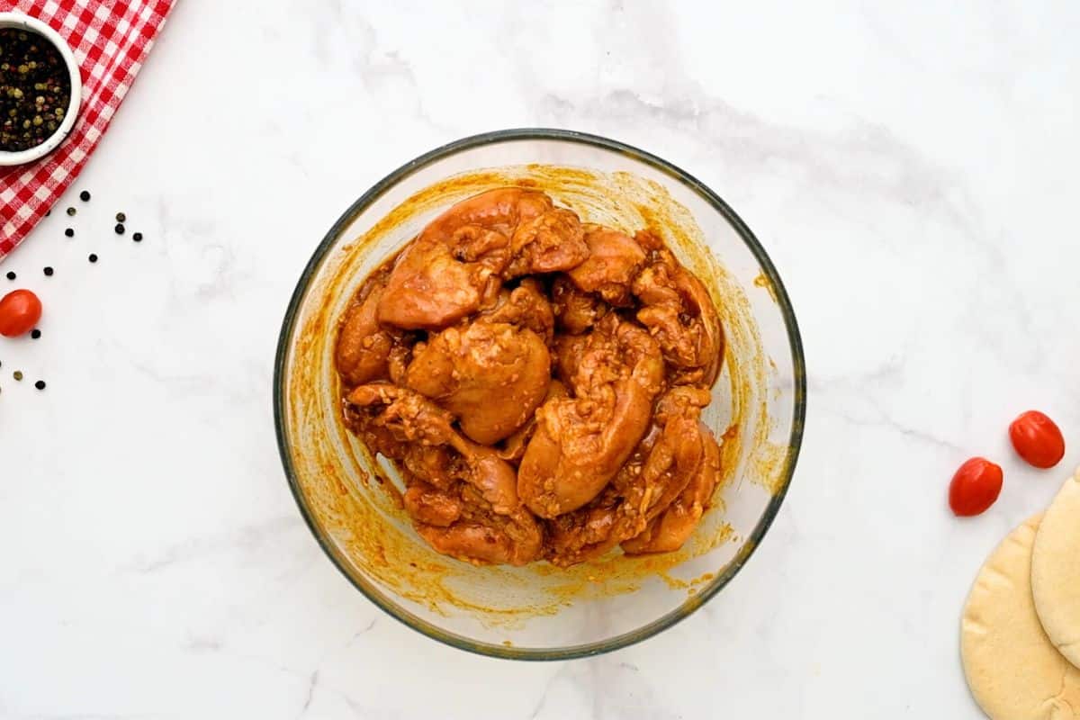 Chicken thighs in chicken shawarma marinade in large mixing bowl.