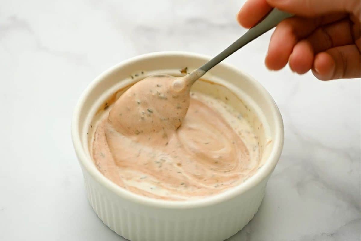 Ranch dressing mixed with BBQ Sauce in small white bowl.