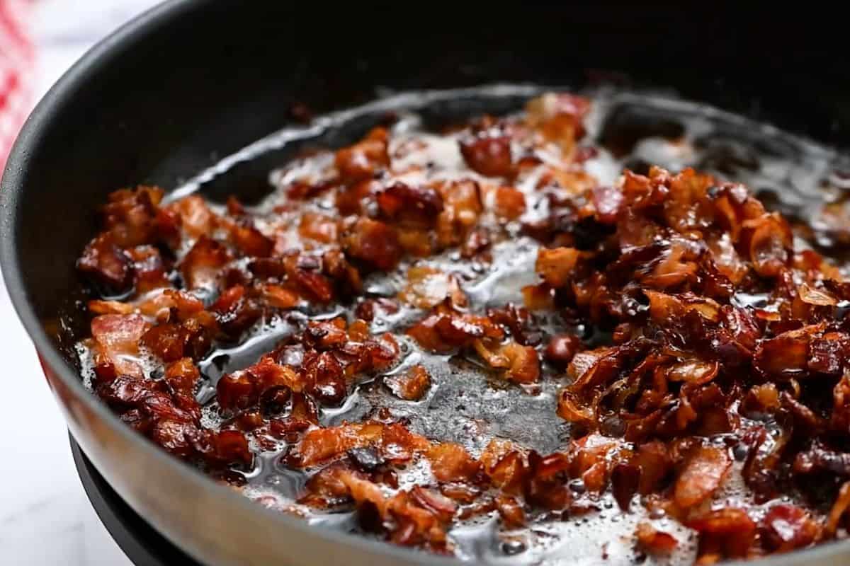 Diced bacon after being browned and cooked in large skillet.