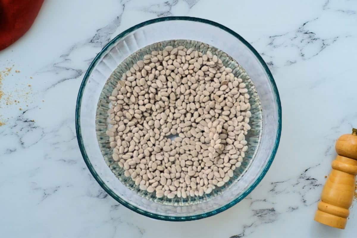 Dried navy beans in large bowl covered with water to soak overnight.