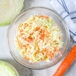 Bowl of homemade creamy coleslaw made with green cabbage and shredded carrots.