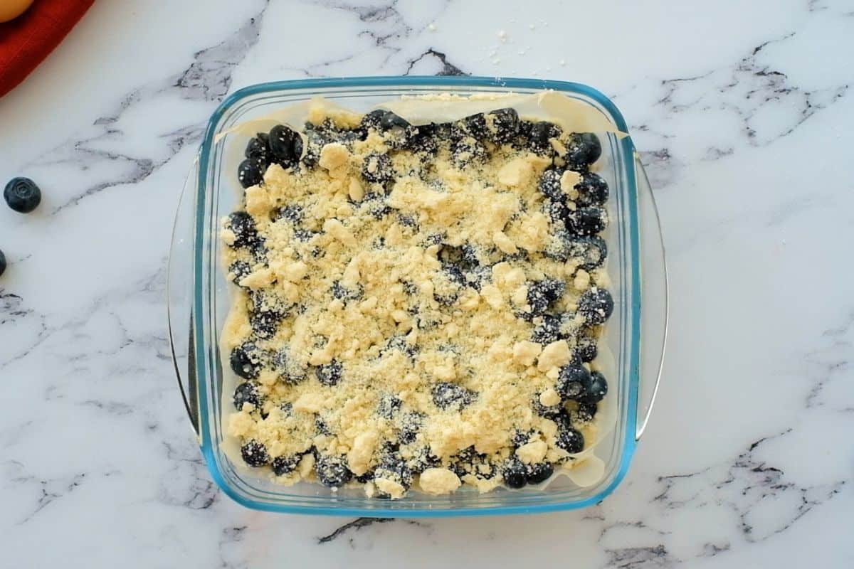 Assembled blueberry pie bars in glass baking dish before baking pie bars.