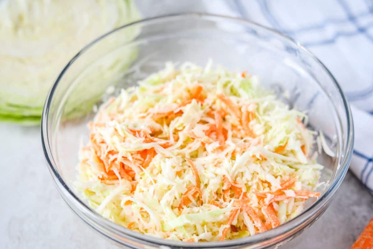 Bowl of homemade creamy coleslaw made with green cabbage and shredded carrots.