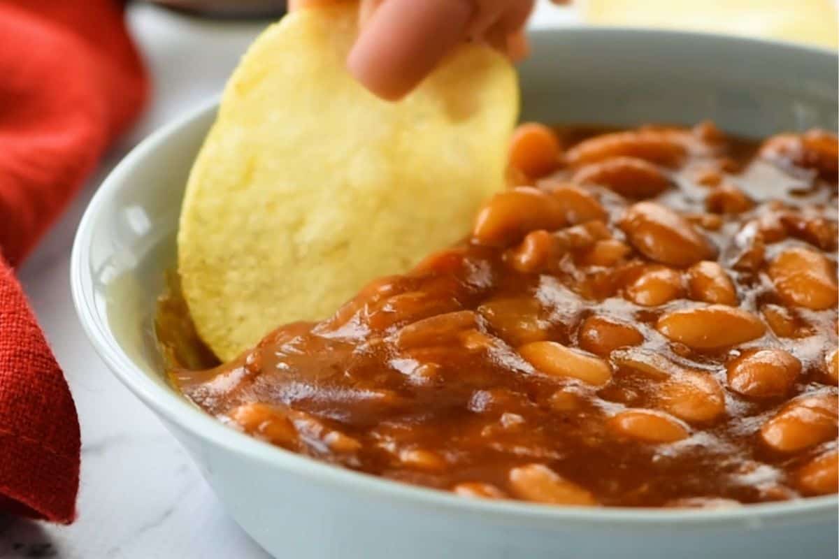 Plain potato chip dipping into rich homemade baked beans.