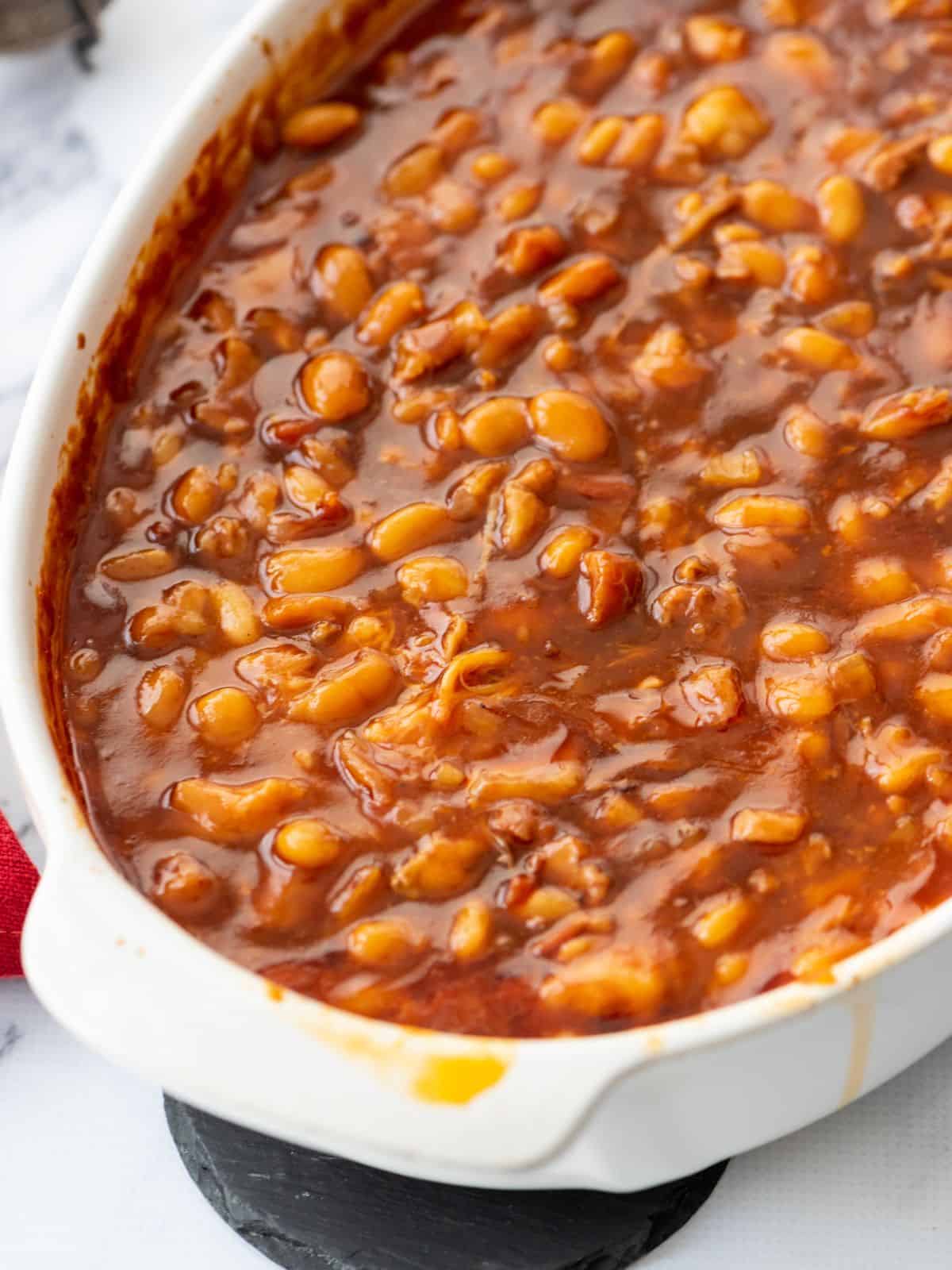 Homemade baked beans in large white casserole dish.