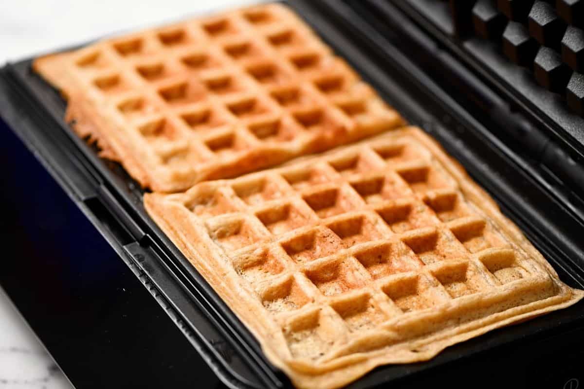 Whole wheat waffles on waffle iron after being cooked.