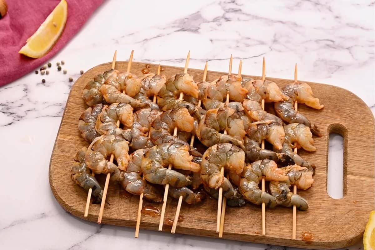 Skewered marinated shrimp on wooden cutting board.