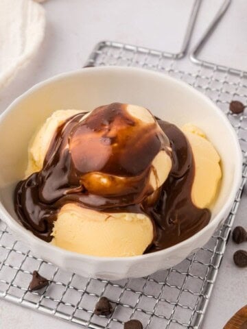 Bowl of vanilla ice cream drizzled with hot fudge sauce.