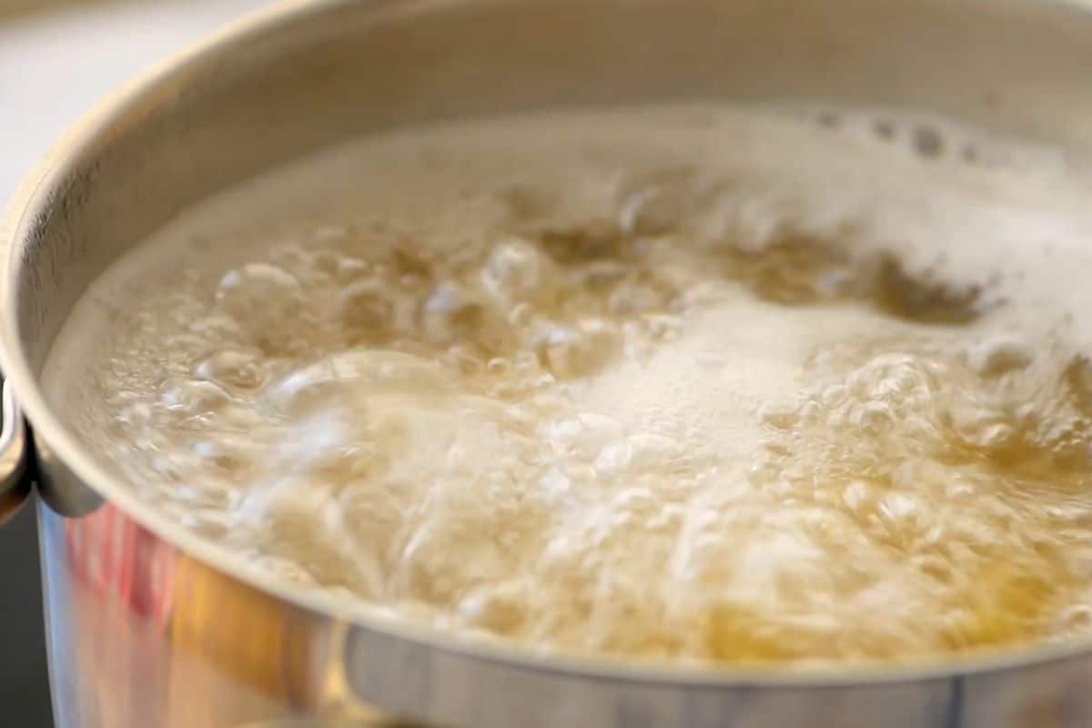 Large pot of boiling water with noodles in salted water.