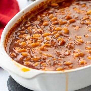 Saucy brown sugar baked beans in large white casserole dish.