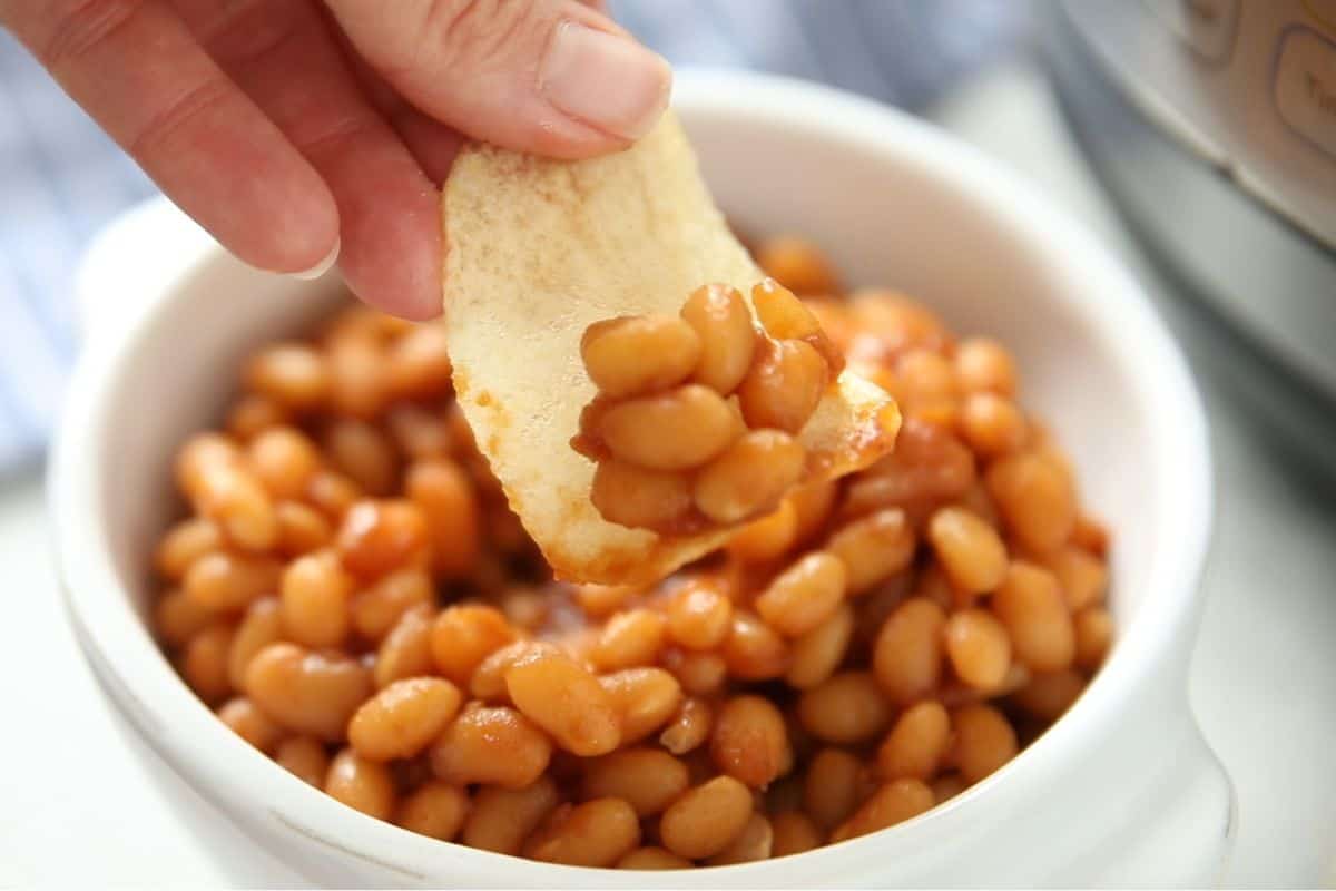 Potato Chip Scooping up baked beans from white bowl.