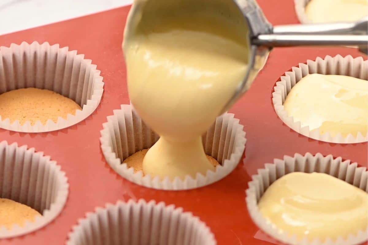 Mini cookie scoop scooping cheesecake batter into mini muffin pan.