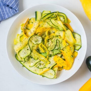 Sauteed summer squash ribbons in white bowl.