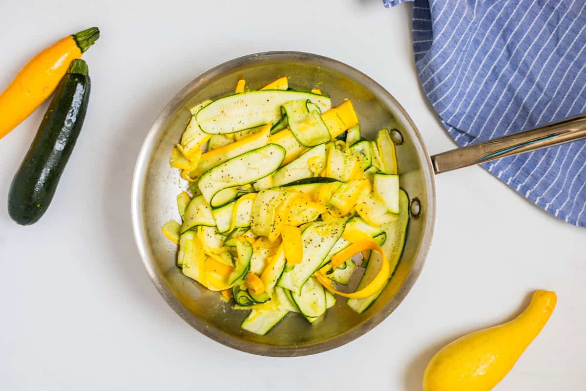 Sauteed ribbons of summer squash in small frying pan topped with parsley.