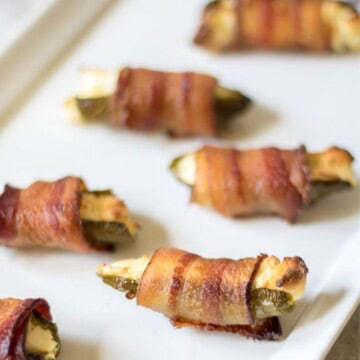 Bacon-Wrapped Jalapeno Poppers on white platter after being baked and toothpicks removed.