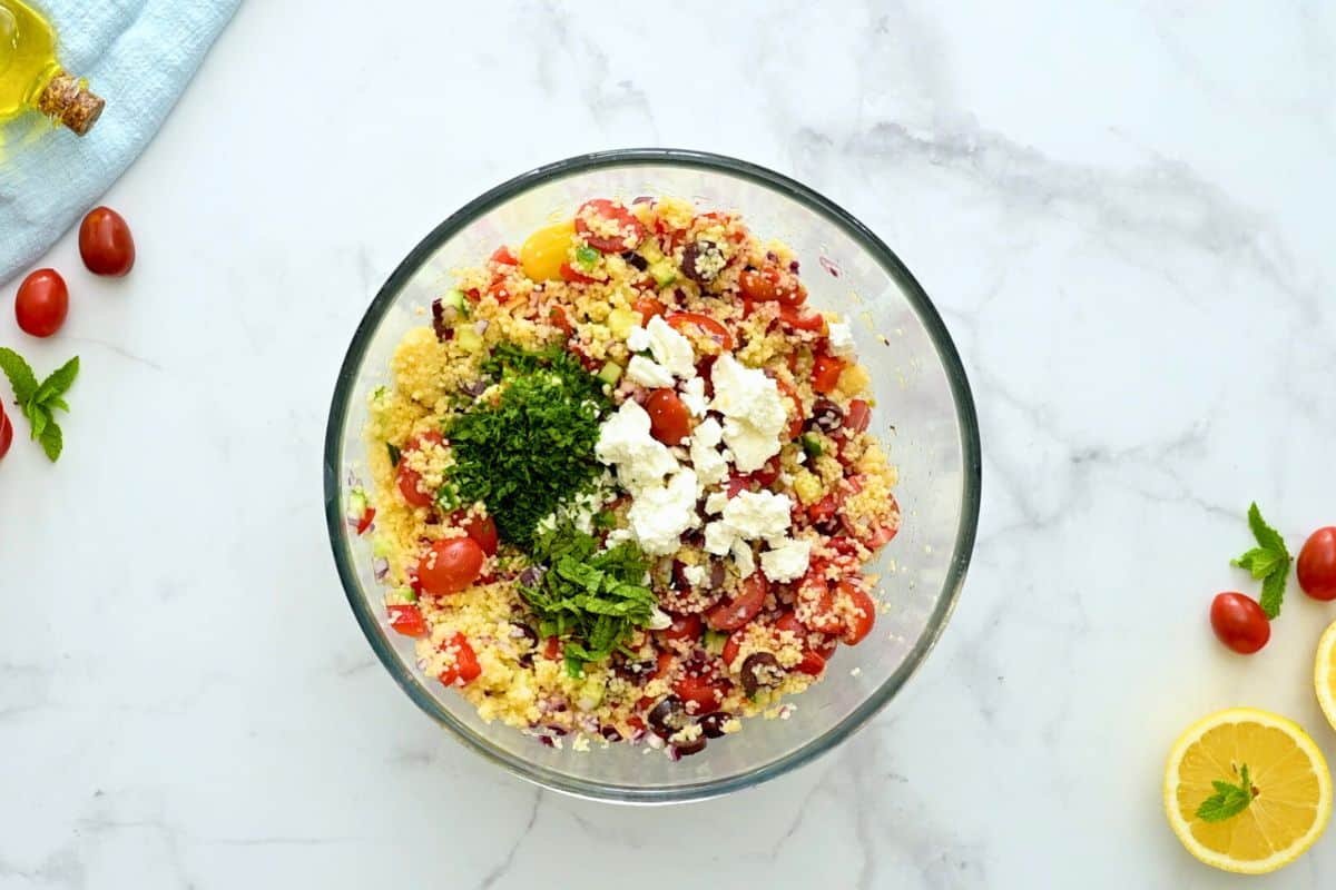 Bowl of cold couscous salad with added feta, mint, and parsley.