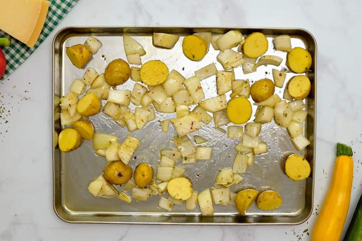 Seasoned potatoes and onions on large rimmed sheet pan.
