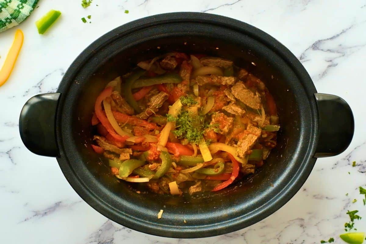 Cooked steak and peppers and onions in crockpot after adding lime juice and lime zest.