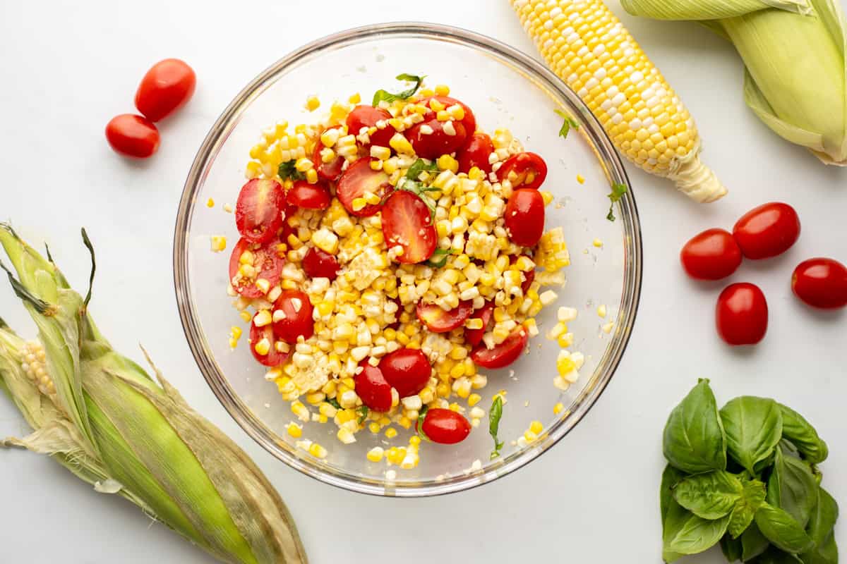 Mixing bowl with corn, tomatoes, and basil mixed together.