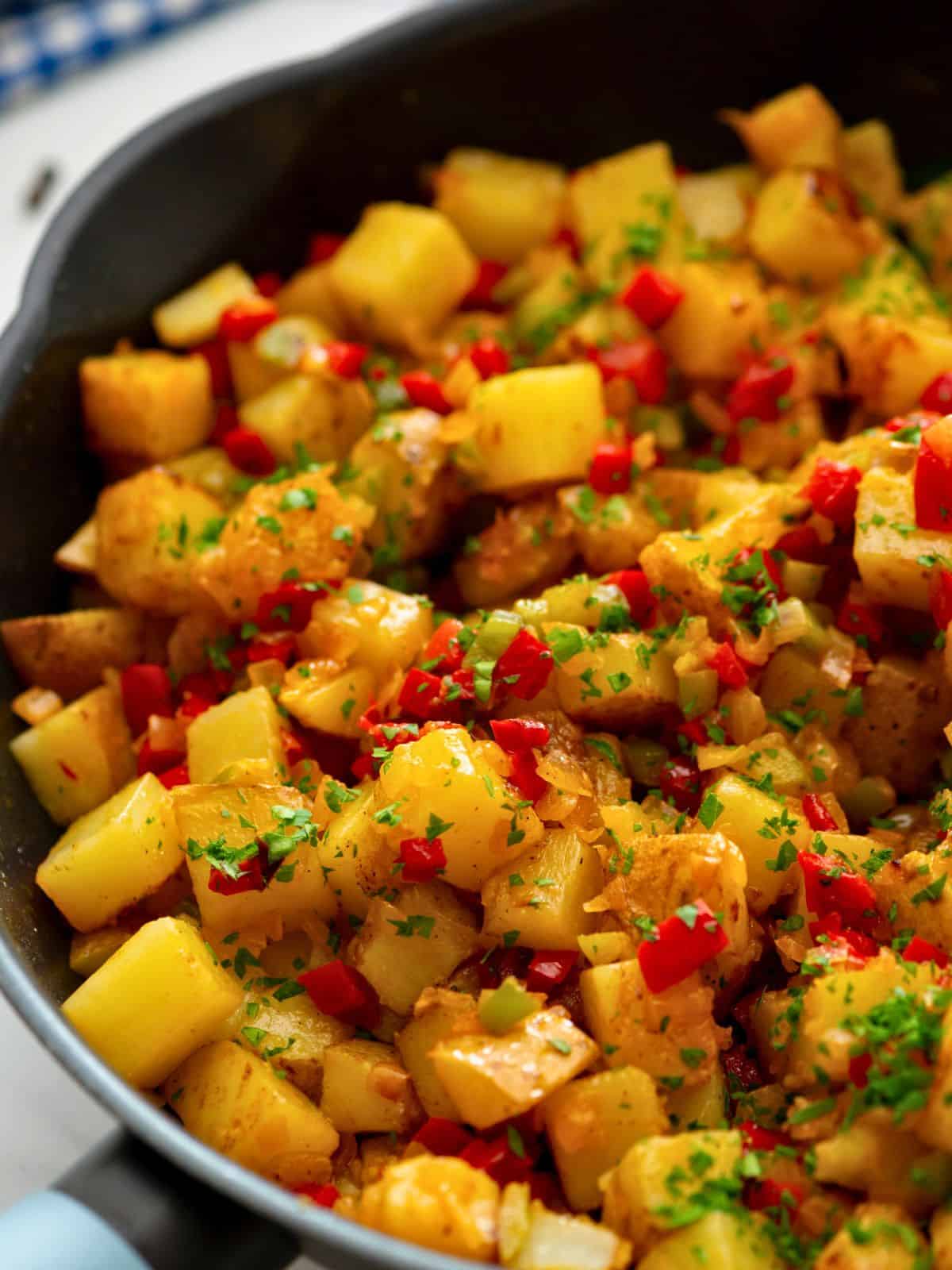 Pan-fried potatoes in large skillet with peppers and onions.