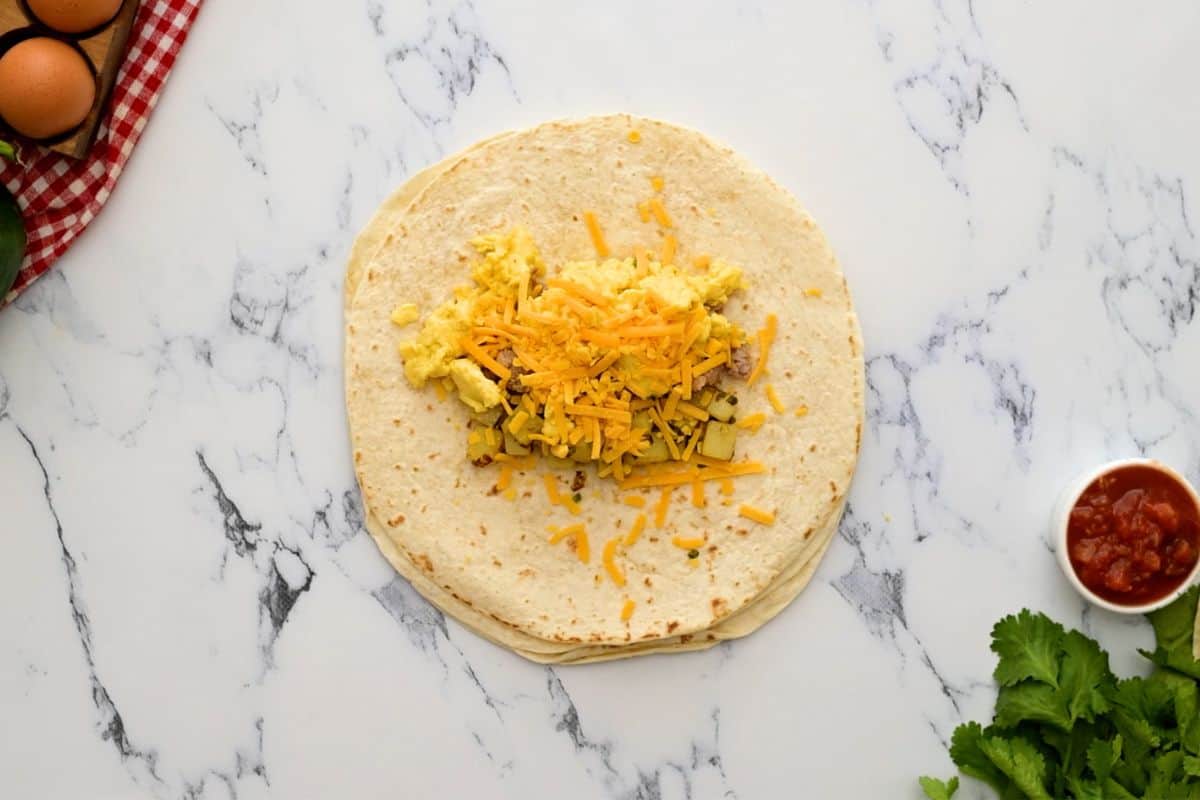 Flour tortilla topped with center filled with potatoes, eggs, sausage, and cheese.