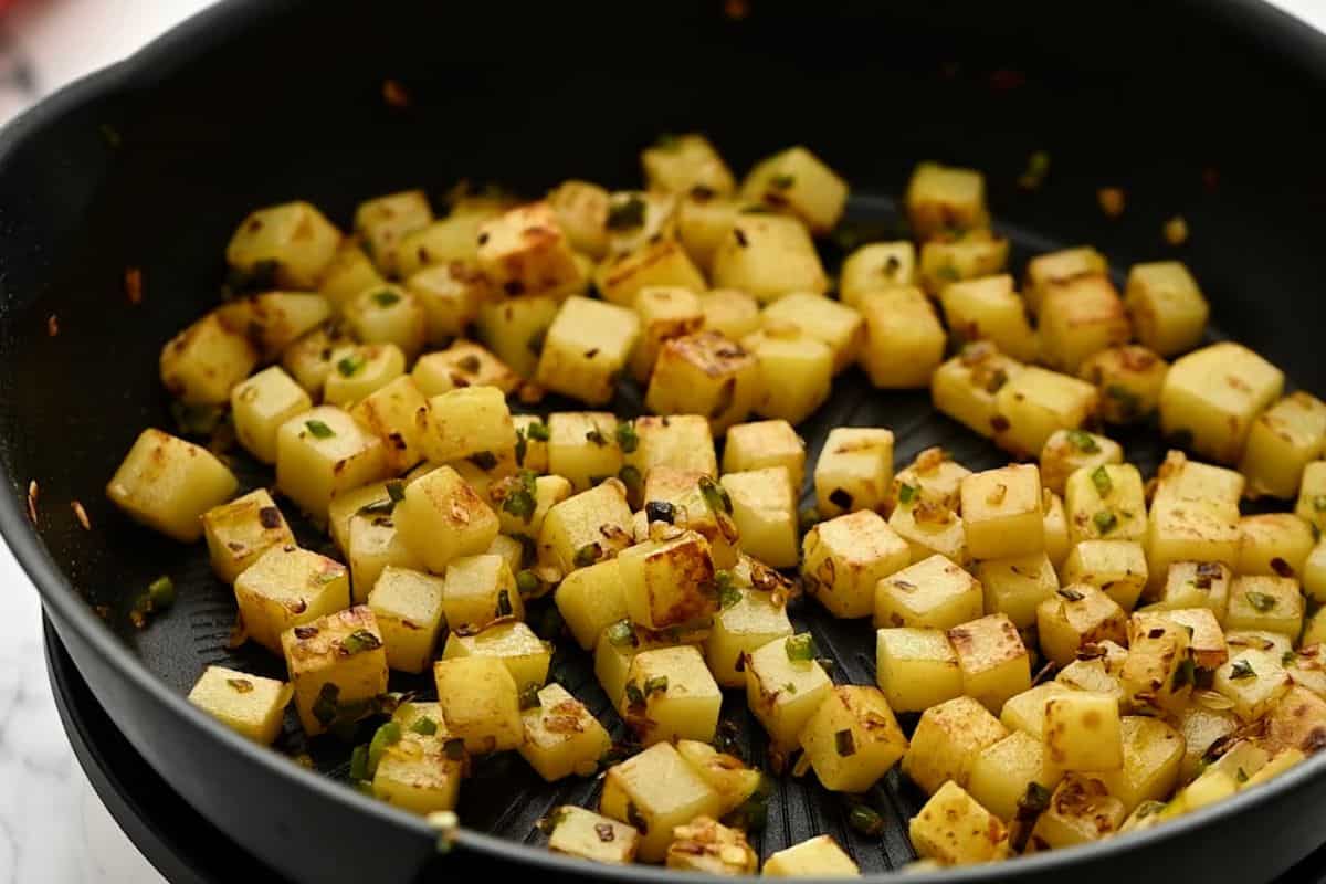 Crispy potato cubes in skillet.