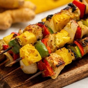 Chicken, pineapple, peppers, and onions skewered on wooden skewers after being grilled.