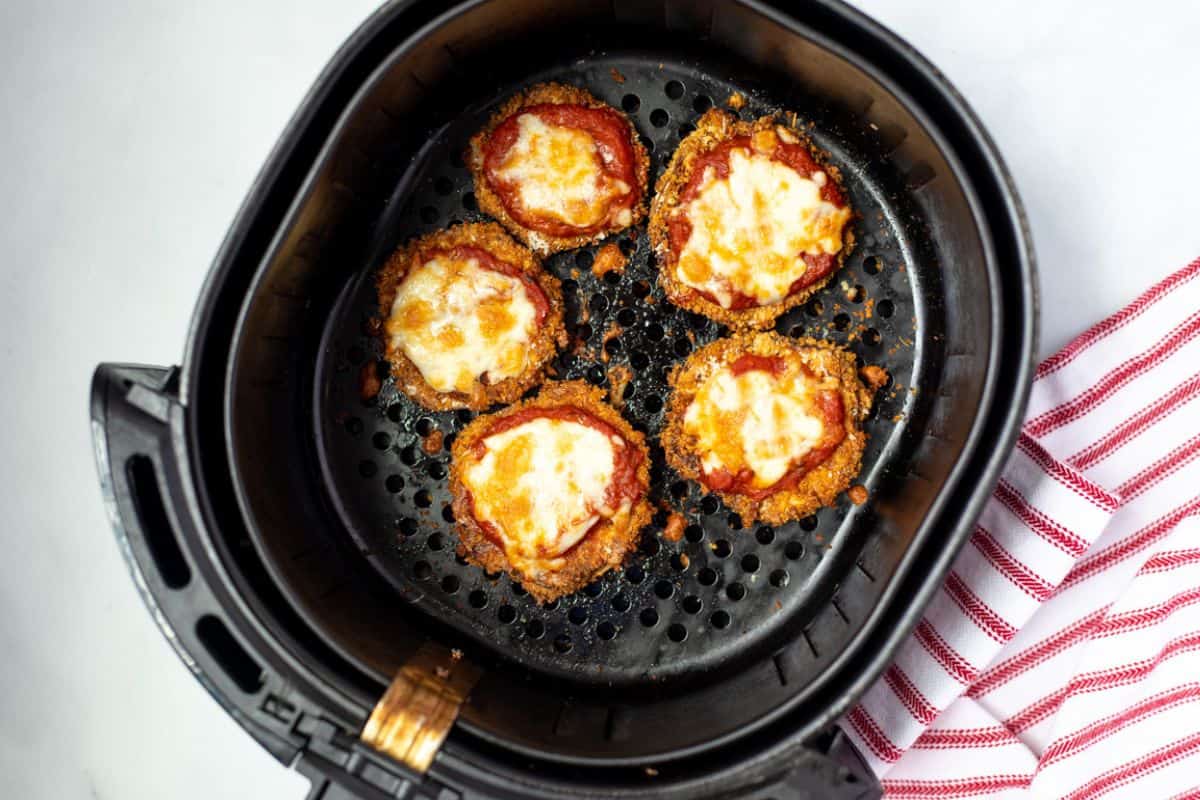 Crispy Eggplant Parmesan After topping with marinara and cheese and air frying inside air fryer basket.