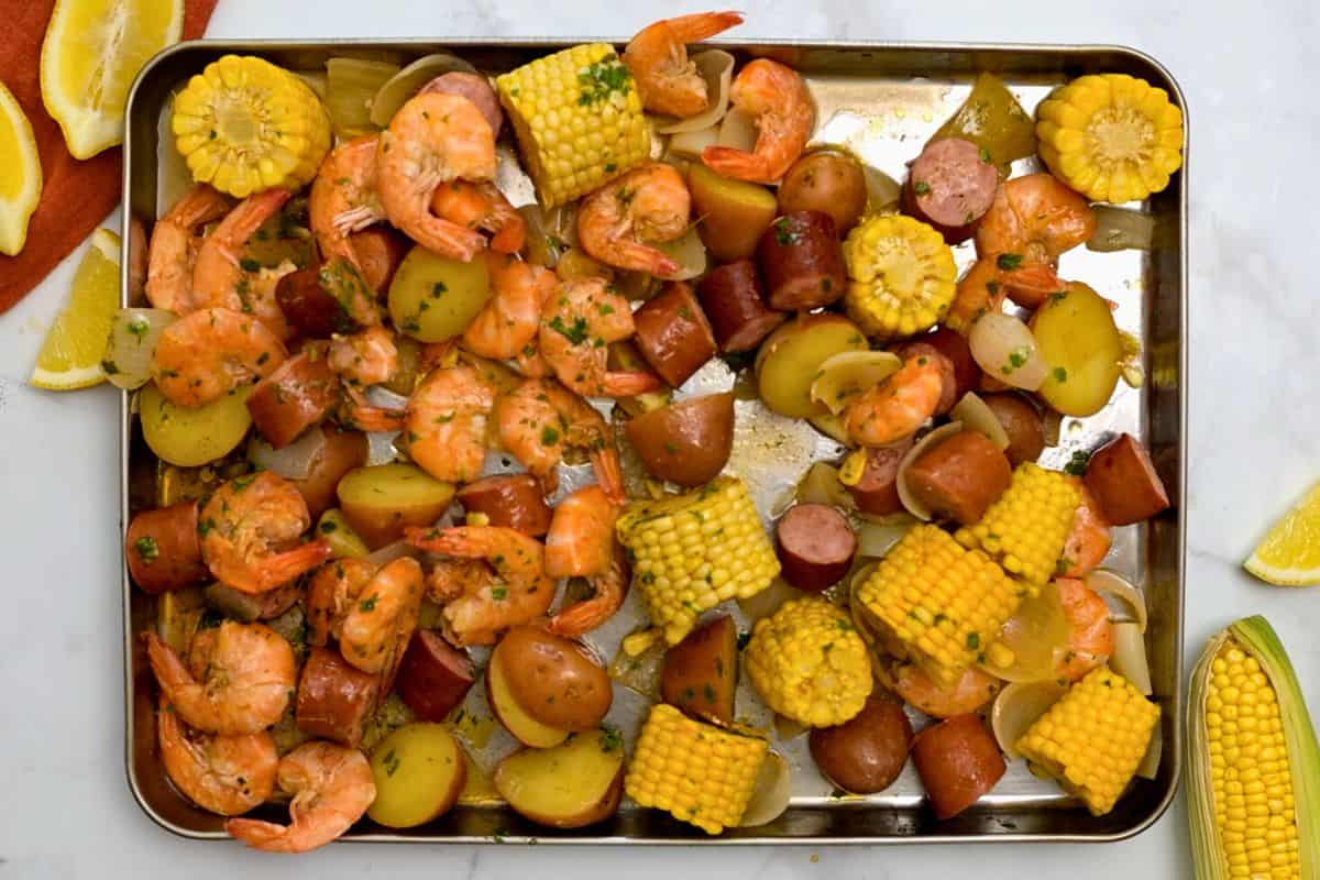 Old Bay Shrimp Boil spread out on sheet pan topped with melted butter and parsley.