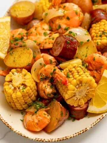 Shrimp Boil after being drained off served on platter with lemon wedges, butter and parsley.