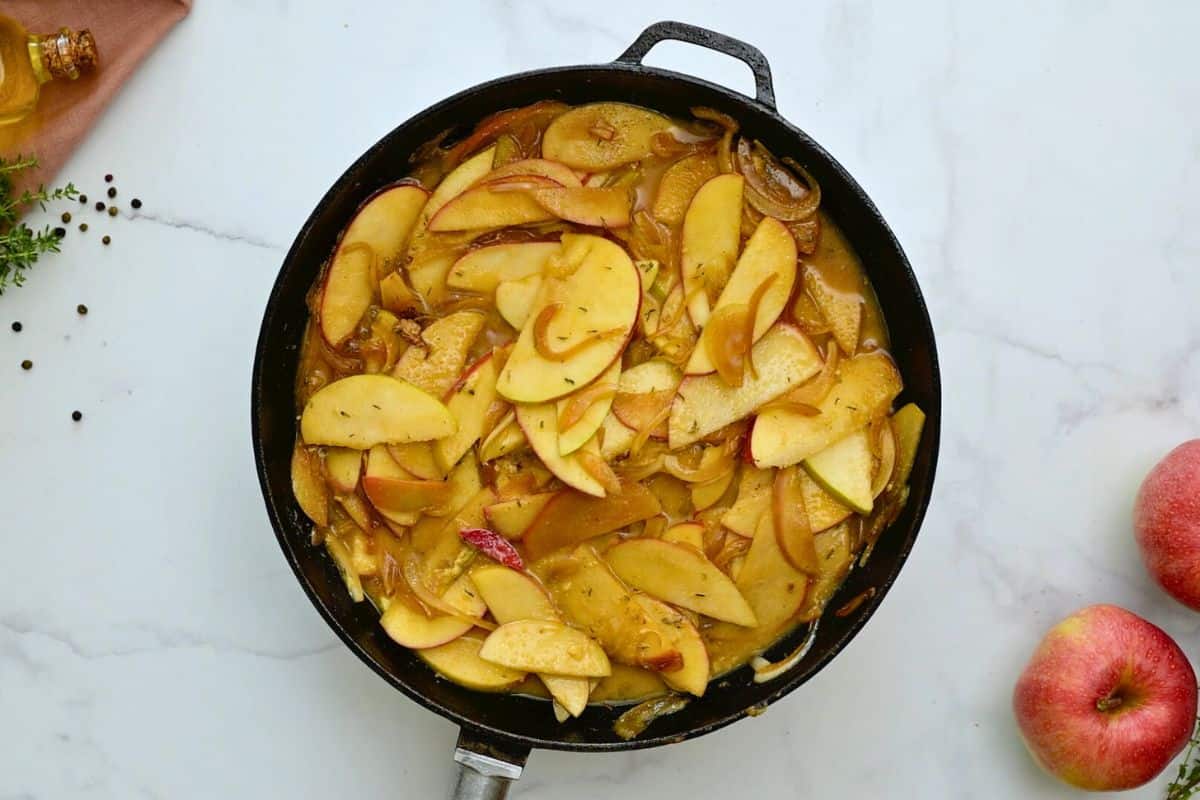 Sauteed apples and onions in skillet with thyme and apple cider.