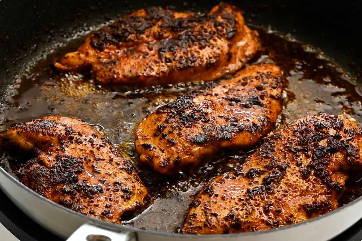 Chicken breasts in skillet after being blackened with Cajun seasoning.