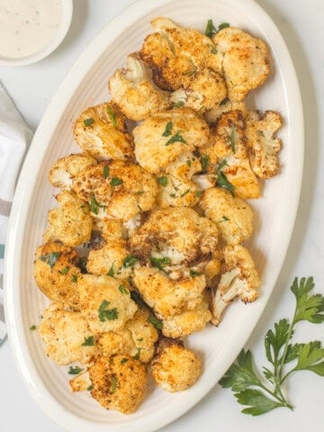 Crispy Air Fryer Cauliflower on white platter topped with minced parsley.